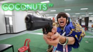 Drag queen aiming a gun, Coconuts TV. Gay travel advice, maxresdefault image. Drag performance, LGBTQ+ travel.