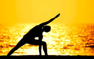 Silhouette of a man doing yoga at sunset in Phuket, Thailand. Gay TropOut travel adventure and healthy lifestyle.