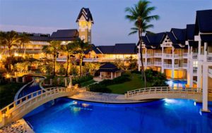Hotel Gay Phuket TropOut: Resort with pools, bridges, and palm trees at dusk. Gay travel destination for men. Tropical paradise.