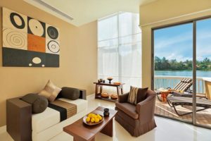 TropOut Hotel Room View: Modern suite with balcony overlooking lake. Gay travel luxury with stylish decor, lounge chair, and serene water views.