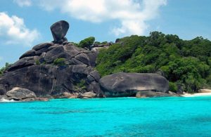 Similan Islands' Sail Rock, a gay travel destination. Turquoise water and lush greenery surround the iconic rock formation. A tropical paradise.