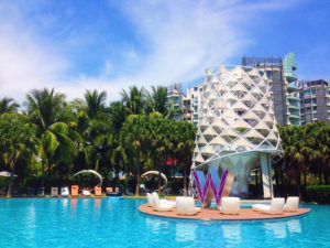 W Singapore pool. Gay travel: Luxury resort with palm trees, pool, and modern architecture. Perfect for a relaxing vacation.