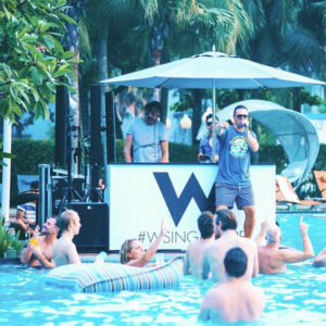 Gay travel: DJ & singer at W hotel pool party. Men enjoying music in the water. #WSing event. Fun gaycation vibes.