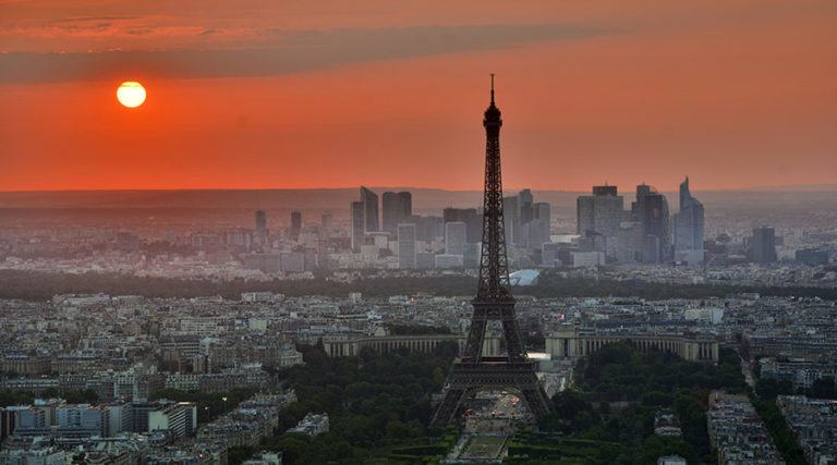 Paris skyline at sunset, featuring the Eiffel Tower and La Défense. Gay travel advice for men in Paris.