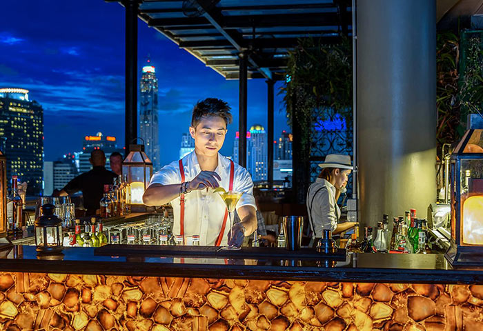 Hotel Muse Bangkok rooftop bar at night. Bartender preparing a cocktail. Perfect Instagram spot for gay travelers. Gay hotel in Bangkok.