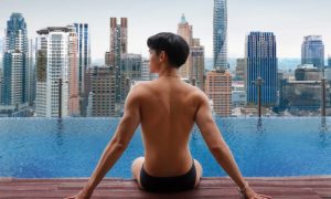 Man at Hotel Indigo Bangkok Wireless Road's rooftop infinity pool. Gay travel advice: luxury hotel with city view.