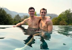 Gay couple at a Chiang Mai gay-friendly hotel. Two men in an infinity pool with a mountain view. Thailand gay travel.