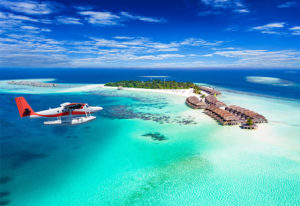 Seaplane over Maldives islands resort. Best seaplane companies transport gay travelers to Maldives. Turquoise ocean and blue sky.