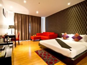 Glitz Hotel room interior. Gay-friendly hotel with bed, red sofa, desk, and patterned wall. Comfortable lodging for gay men's travel.