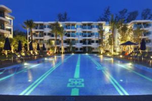 Holiday Inn Express Krabi Ao Nang Beach pool at night. Gay-friendly hotel with illuminated pool, palm trees, and lounge chairs. Serene Krabi vacation.