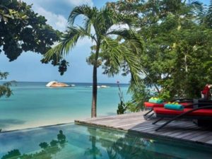 Kupu Kupu Phangan Beach Villas & Spa by L’Occitane: Gay-friendly hotel with pool, ocean view, lounge chairs, and palm trees on Koh Phangan.