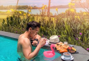 Gay man relaxing at Pullman Phuket Panwa Beach Resort, a SHA-certified gay-friendly hotel. Breakfast, flamingo float, and ocean view.
