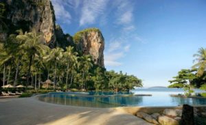 Rayavadee Hotel pool view. Gay-friendly hotel with beach access, lush greenery, and towering cliffs. Perfect for gay men's travel.