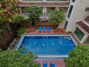 The Agate Pattaya Boutique Resort pool view. Gay-friendly hotel with waterfall feature, sun loungers, and lush greenery. Ideal for gay travelers.