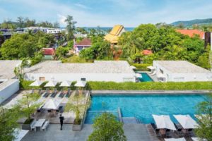 X2 Vibe Phuket Patong hotel view. Gay-friendly hotel with pool, lounge chairs, and tropical foliage. A relaxing gay travel destination.