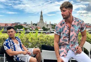 Gay-friendly Sala Rattanakosin Bangkok hotel view. Two men in shirts with Wat Arun in the background. Bangkok travel for gay men.