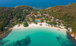 Aerial view of a beachfront gay hotel in Koh Samet. Turquoise water, white sand, lush greenery. A tropical paradise for gay travelers.