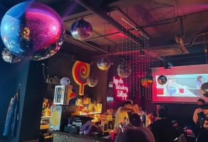 Interior of Lollipop Bar & Lounge, a popular gay cocktail bar in Shanghai. Disco balls, bar with patrons, and a lollipop sign.