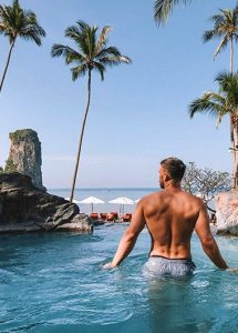 Gay man at Centara Grand Beach Resort & Villas Krabi. Private beach hotel view of palms, ocean, and pool. Travel advice for gay men.