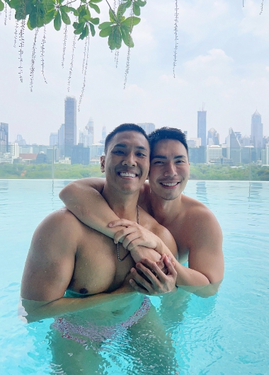 Gay honeymoon at SO/ Bangkok, a luxury hotel in Silom. Two shirtless men embrace in an infinity pool, city skyline in the background.