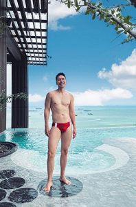 Gay-friendly Hilton Pattaya beachfront hotel. Man in swimwear by the swimming pool. Top luxury travel destination for gay men's holidays.
