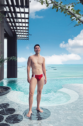 Gay-friendly Hilton Pattaya beachfront hotel. Man in swimwear by the swimming pool. Top luxury travel destination for gay men's holidays.