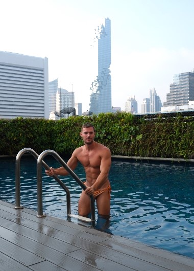 Le Méridien Bangkok gay hotel rooftop pool. Muscular man at luxury Bangkok hotel near Silom gay bars. Gay travel in Thailand.
