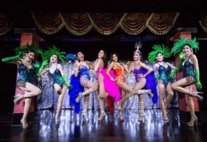 Blue Dragon Cabaret show in Krabi, Thailand. Performers in colorful costumes and headdresses pose on stage. Gay travel destination.