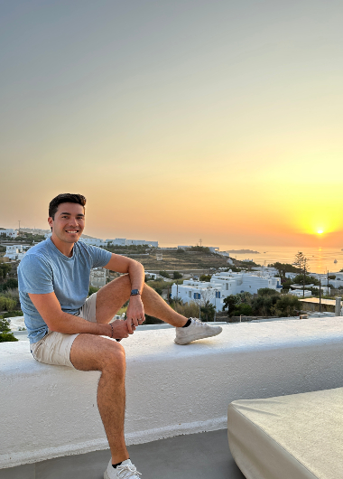 Gay couple honeymoon at Andronikos Hotel, Mykonos. Man enjoying sunset view. Top gay hotels for LGBTQ+ travel, romantic getaway.