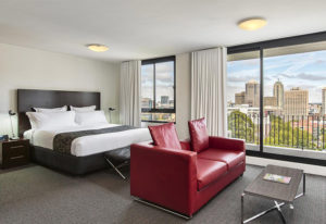 Cambridge Hotel room with city view. Gay-friendly hotel offers modern rooms, comfy beds, red sofa, and a welcoming atmosphere for gay travelers.