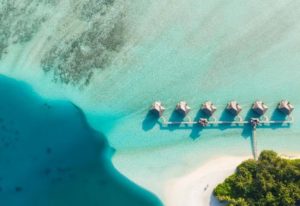 Aerial view of Conrad Maldives Rangali Island Resort's overwater bungalows. A gay-friendly hotel with turquoise waters and white sand.