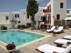 Despotiko Hotel, a gay-friendly hotel. Swimming pool with sun loungers in a whitewashed building with red accents. Ideal for gay men travel.