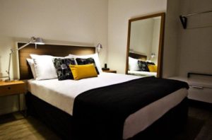 Ovolo Laneways pet-friendly hotel room. Gay-friendly hotel with a bed, pillows, and a mirror. Ideal accommodation for gay travelers and their pets.