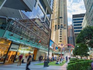 Rydges World Square, a gay-friendly hotel. Outdoor view of the hotel with a rainbow arch and people enjoying the space. Sydney, Australia.