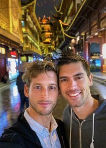 Gay honeymoon at W Shanghai The Bund. Two men smile in a Shanghai street at night, illuminated by warm lights.