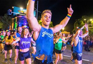 Sydney Mardi Gras Parade. People dancing, wearing rainbow accessories. Gay Sydney travel guide. Party schedule.
