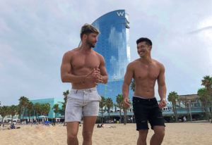 Gay couple at W Barcelona, most booked luxury hotel for honeymoon. Two shirtless men on the beach in front of the W Hotel in Barcelona.