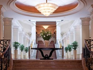 Corinthia Hotel Budapest's grand lobby. A gay-friendly, pet-friendly hotel with marble staircases, ornate columns, and a large chandelier.