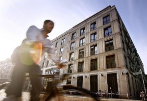 Hotel AMANO, a gay-friendly and pet-friendly hotel. Exterior view with a blurred cyclist passing by. Great for gay men travel advice.