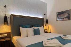 Hotel Memories Budapest gay-friendly hotel room. Twin beds with white linens, blue accents, and modern lamps. Comfortable stay in Budapest.