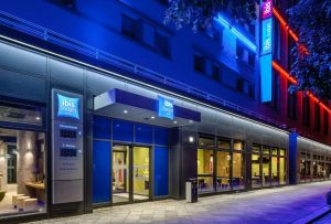 Ibis budget Berlin Kurfurstendamm, a gay-friendly hotel. Facade with neon lights. Modern design, perfect for gay travelers in Berlin.