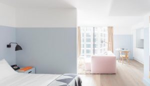 Leman Locke hotel room interior. Modern design with pink sofa, light wood floors, and a view of the city. Gay-friendly travel advice.