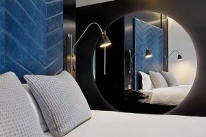 The Hoxton, Shoreditch hotel room. Gay-friendly hotel with a modern design, blue headboard, stylish lamps, and large round mirror. London travel.