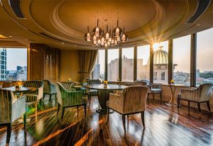 Elegant lounge at Caravelle Saigon Hotel, a gay-friendly travel destination. Features city views, stylish seating, and warm lighting.