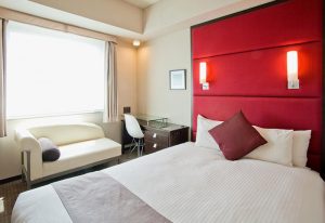 Citadines Central Shinjuku Tokyo room. Gay-friendly hotel with bed, sofa, desk, and red headboard. Ideal for gay travelers in Shinjuku, Tokyo.