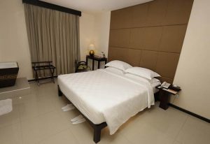 East Hotel's bedroom: Gay-friendly hotel room featuring a double bed with white linens, a brown headboard, and neutral decor. Ideal for gay travel.