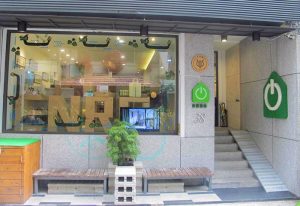 Energy Inn, a gay-friendly hotel. Building facade with benches, a ramp, and a window display. Number 38 is visible. Green power button logo.
