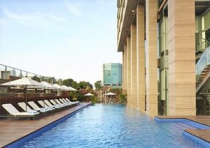 Poolside view at Fraser Residence Menteng Jakarta, a gay-friendly hotel. Lounge chairs and umbrellas offer relaxation in this urban oasis.