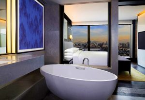 Grand Hyatt Seoul gay-friendly hotel room. Bathtub in foreground, bed and Seoul city view in background. Luxury travel.