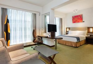 Holiday Inn Express Hong Kong Soho gay-friendly hotel room. Features a bed, desk, chair, sofa, and modern decor for a comfortable stay.